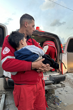 PRCS paramedic with small child during operation of WHO, OCHA and PRCS mission to Nasser Hospital to assess patients and refer critical patients. https://www.emro.who.int/media/news/who-transfers-critical-patients-out-of-nasser-medical-complex-fears-for-safety-of-remaining-patients.html